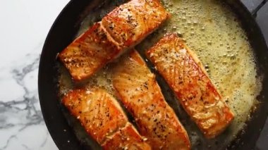 Sarımsaklı somon tavası yumuşak ve sulu olana kadar pişirilir, tereyağı aromalı sıcak servis edilir. Restoran menüleri, sağlıklı deniz ürünleri, gurme yemek görselleri ve somon tabaklarının sergilendiği ticari stok görüntüleri için ideal..