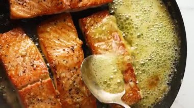 Tavada pişirilmiş sarımsaklı somon balığı yumuşak balık ve bol tereyağı sosuyla hazırlandı. Restoran usulü sıcak servis edildi. Deniz ürünleri menüleri, güzel yemek görselleri ve somon mutfağını vurgulayan ticari stok görüntüleri için mükemmel..