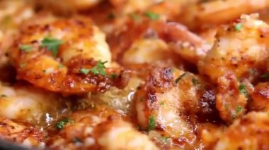 Zengin tereyağı sosu ve biber sosuyla pişirilmiş sarımsaklı karides ve karides sulu dokularla sıcak servis edilir. Deniz ürünleri menüleri, restoran promosyonları, konforlu yemek görselleri ve tereyağlı karides tabakları sergilenen ticari stok görüntüleri için ideal..