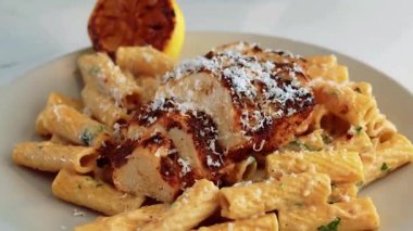 Limonlu tavuk ve limon sosuyla hazırlanmış limonlu makarna kremalı sıcak servis ediliyor. İtalyan tarzı menüler, konforlu yemek görselleri, restoran promosyonları ve makarna sergilenen ticari stok görüntüleri için ideal..