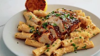 Zengin soslu ve narenciye soslu kremalı tavuk makarnası. Restoran tarzı sunumda sıcak servis ediliyor. Makarna menüleri, yemek pazarlama görselleri ve tavuk makarnalarını vurgulayan ticari stok görüntüleri için mükemmel..