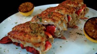 Sarımsaklı ıstakoz kuyruğu yumuşak ve sulu olana kadar pişirilir, tereyağı aromalı sıcak servis edilir. Lüks restoran menüleri, güzel yemek görselleri, gurme deniz ürünleri promosyonları ve ticari stok görüntüleri için ideal..