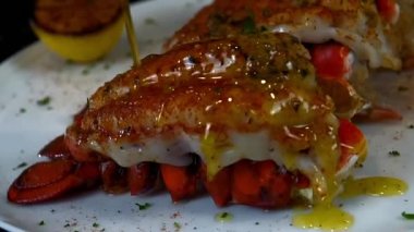 Klasik sarımsaklı ıstakoz kuyruğu mükemmel pişmiş ve güzel bir deniz ürünleri yemeği olarak servis edilmiş. Lüks menüler, gurme yemek görselleri ve kaliteli ıstakoz mutfağı sergilenen ticari stok görüntüleri için ideal..