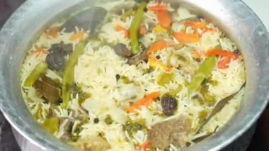 Geleneksel koyun eti biryani katmanlı pirinç ve zengin baharatlarla pişirilir, aromatik aromalı sıcak servis edilir. Hint yemek promosyonları, restoran menüleri ve klasik biryani hazırlığını ön plana çıkaran ticari stok görüntüleri için ideal..