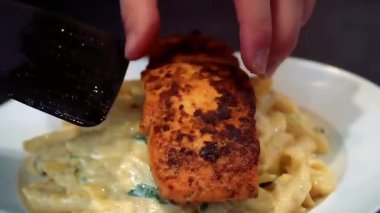 Kremalı sosla pişirilmiş ve sıcak servis edilen somon balığı makarnası lezzetli bir deniz ürünleri makarnası deneyimi sunuyor. Gündelik yemek ve ticari gıda stoku görüntüleri için ideal..