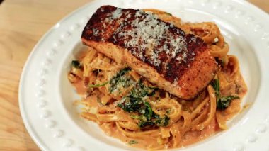 Gurme somon makarnası, bol kremalı sos ve zarif bir sunumla sıcak servis edilir. Güzel yemek görselleri ve stok görüntüleri için ideal..