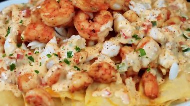 Karides ve yengeçle kaplanmış nihai deniz mahsulü nacho tabağı, dolu bir parti aperatifi olarak servis ediliyor. Paylaşım ve restoran menüleri için mükemmel..