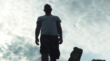 Bir tepenin üzerinde ellerini sakallı adam yükseltir