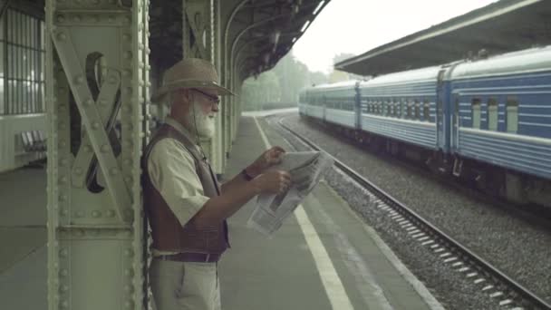 Oude Man met krant op treinstation — Stockvideo