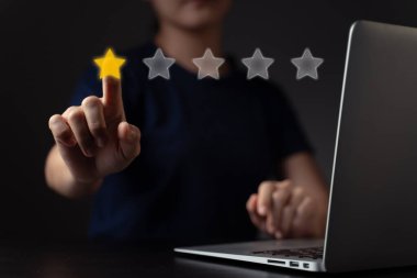 Dizüstü bilgisayar kullanan bir kadın, yıldız simgesi hologram efektli yorumlar.