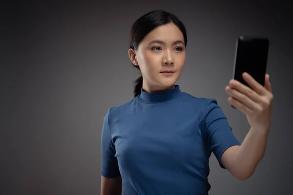 アジアの女性は顔認識システムを使用してスマートフォンで顔をスキャンします 背景に隔離された — ストック写真