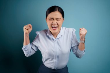 Asyalı kadın öfkeli ve bağırıyor mavi arka planda..