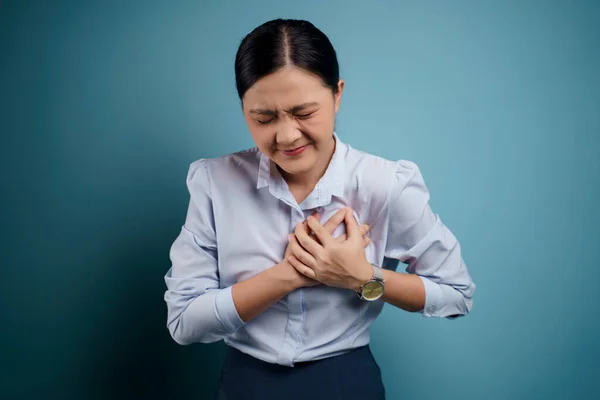 亚洲妇女的胸部疼痛 孤立地站在蓝色的背景下 — 图库照片