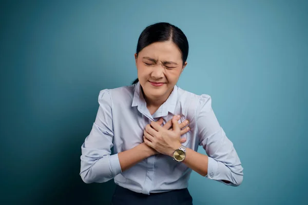 亚洲妇女的胸部疼痛 孤立地站在蓝色的背景下 — 图库照片
