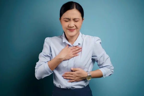 亚洲妇女患了胃痛 双手紧握着腹部 背景上与外界隔绝 — 图库照片
