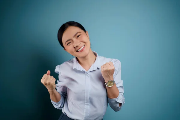 アジアの女性幸せな自信立って示す彼女の拳作るA勝利ジェスチャー隔離された上の青の背景 — ストック写真