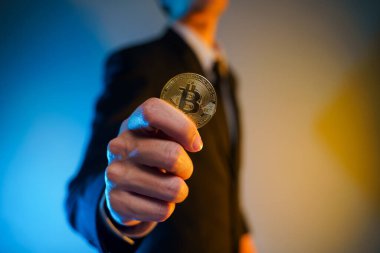 Siyah takım elbiseli bir iş adamının arka planda izole edilmiş altın para tutarken yakın plan çekimi..