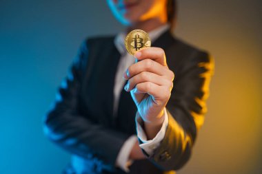 Siyah takım elbiseli iş kadınının arka planda izole edilmiş altın para tutarken yakın plan çekimi..