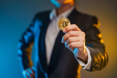 Siyah takım elbiseli iş kadınının arka planda izole edilmiş altın para tutarken yakın plan çekimi..