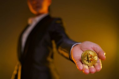 Siyah takım elbiseli iş kadınının arka planda izole edilmiş altın para tutarken yakın plan çekimi..