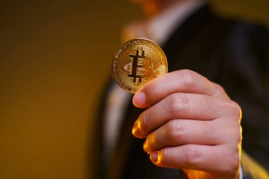 Siyah takım elbiseli iş kadınının arka planda izole edilmiş altın para tutarken yakın plan çekimi..