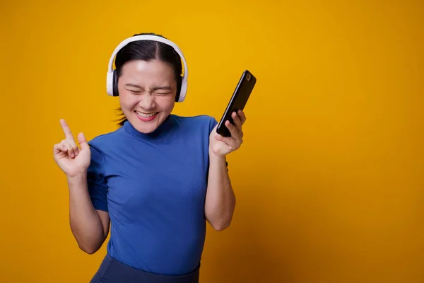 Ασιάτισσα Γυναίκα Ακουστικά Ακούγοντας Μουσική Από Έξυπνο Τηλέφωνο Απομονωμένο Κίτρινο — Φωτογραφία Αρχείου