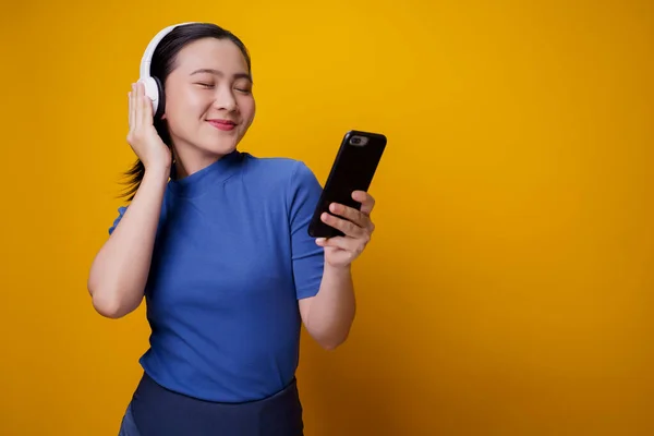 Kulaklıklı Asyalı Kadın Sarı Arka Planda Izole Edilmiş Akıllı Telefondan — Stok fotoğraf