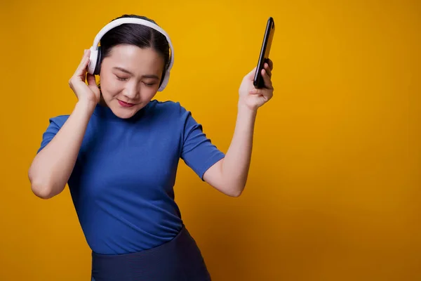 Ασιάτισσα Γυναίκα Ακουστικά Ακούγοντας Μουσική Από Έξυπνο Τηλέφωνο Απομονωμένο Κίτρινο — Φωτογραφία Αρχείου