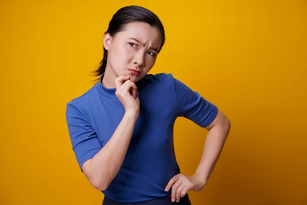 Förvirrad Asiatisk Kvinna Tänker Och Står Isolerad Gul Bakgrund — Stockfoto