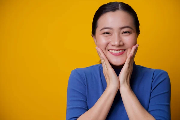 幸せなアジアの女性ショーおもちゃの笑顔立って孤立した上に黄色の背景 — ストック写真