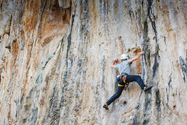 Jovem escalando em uma parede — Fotografia de Stock