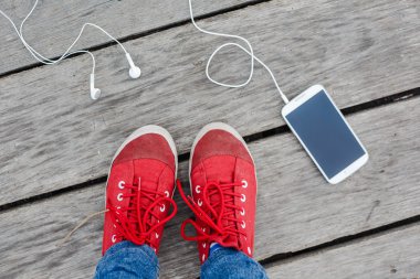 kırmızı spor ayakkabılar ve akıllı telefon 