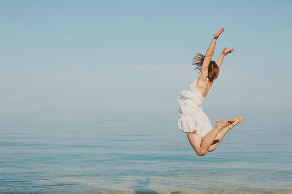 Jonge vrouw springen op het strand — Stockfoto