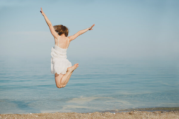 young woman jumping on the beach