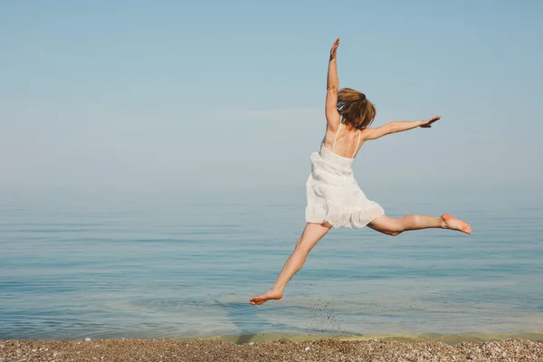 Mujer joven saltando en la playa — Foto de Stock