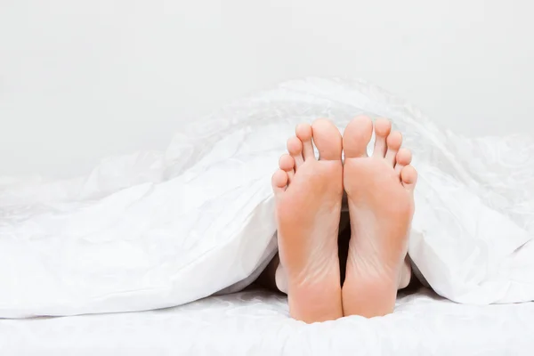 Två fötter i en säng — Stockfoto