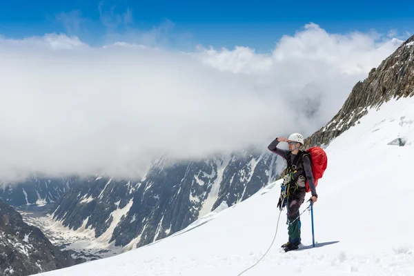 Escalador no topo da montanha nevada — Fotografia de Stock