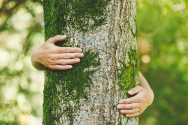 Kadın ağaca sarılıyor. 