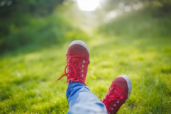 Девушка в кроссовках лежит на траве — стоковое фото