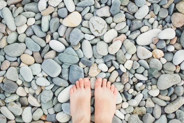 Frauenfüße auf Meeressteinen — Stockfoto