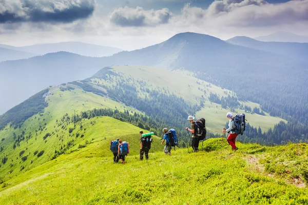 Backpackers hiking on the path in summer mountains — Stock Photo, Image