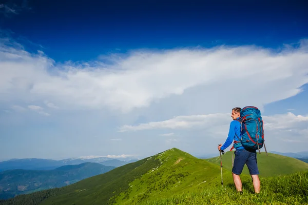 Természetjáró fiatal férfi keresi a hátizsák és a túrázás lengyelek a — Stock Fotó