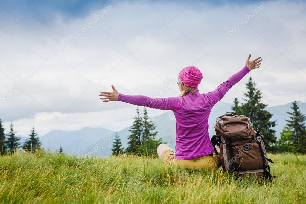 Woman Traveler with Backpack hiking in the Mountains with beautiful summer landscape