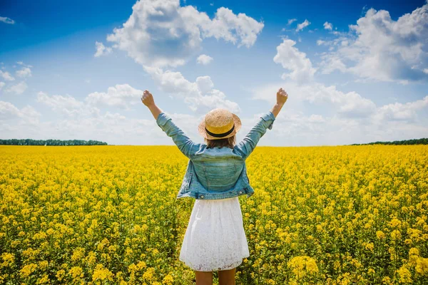 穿着夏装的快乐姑娘 张开双臂 带着鲜花在田野里散步 — 图库照片