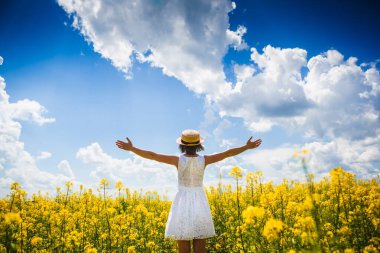 Yaz zamanı konsepti. Beyaz elbiseli genç kız güneşin ve güzel yaz manzarasının tadını çıkarıyor.