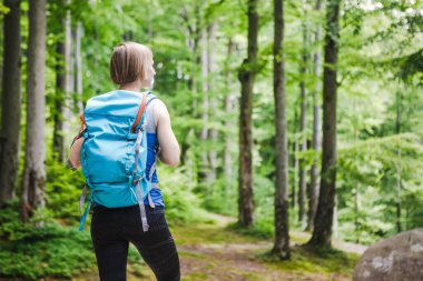 Dağ ormanlarında yürüyen bir kadın yürüyüşçü.