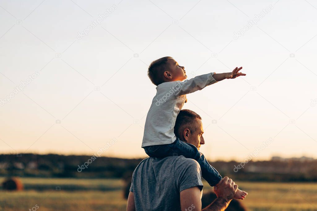 Father and son playing in the park at the sunset time. Family, trust, protecting, care, parenting, summer vacation concept