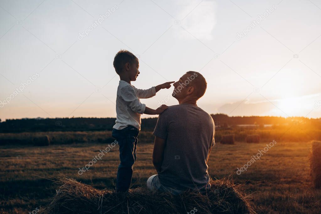 Father and son playing in the park at the sunset time. Family, trust, protecting, care, parenting, summer vacation concept