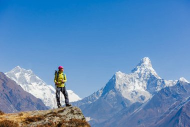 Sırt çantasıyla dağlarda yürüyüş yapan kadın gezgin. Arka planda Himalayalar 'ın güzel yaz manzarası.