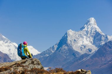 Sırt çantasıyla dağlarda yürüyüş yapan kadın gezgin. Arka planda Himalayalar 'ın güzel yaz manzarası.